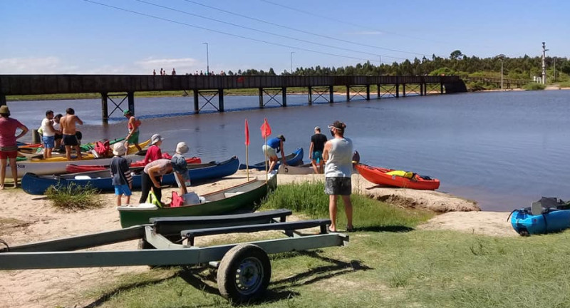 Varias personas junto a sus kayak y canoas, aprontandose para navegar el arroyo.