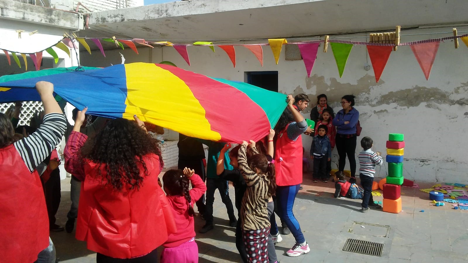 Niños y niñas jugando con tela multicolor.