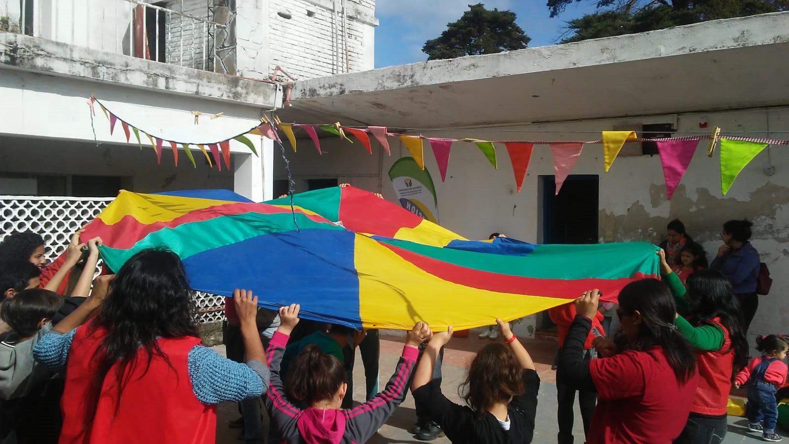 Niños y niñas jugando con tela multicolor.